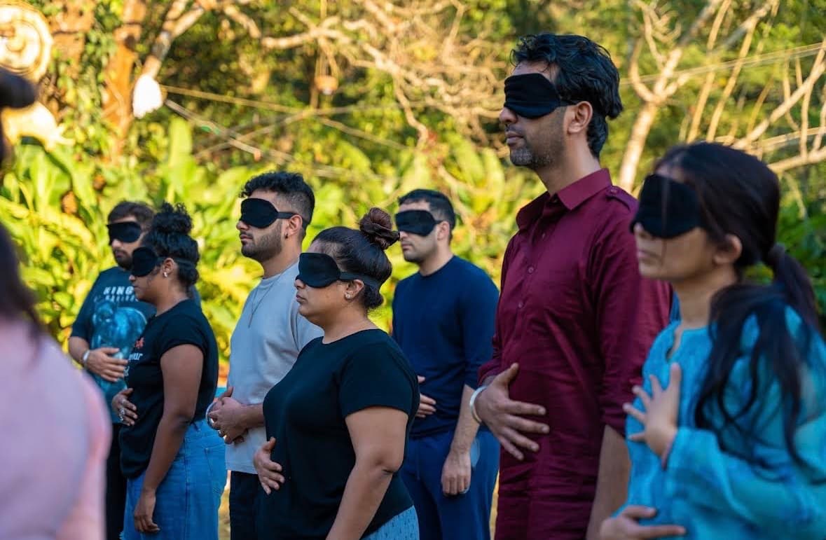 Group in blindfolds during a guided healing session outdoors